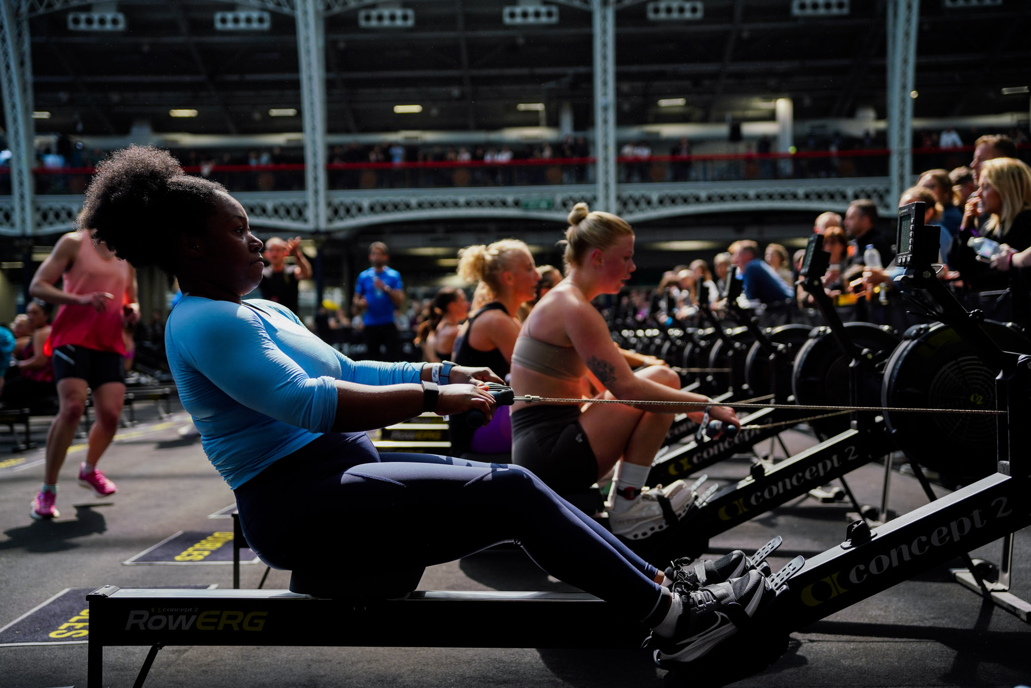 HYROX athlete driving a weighted sled at a HYROX fitness race competition with spectators and PUMA branding visible