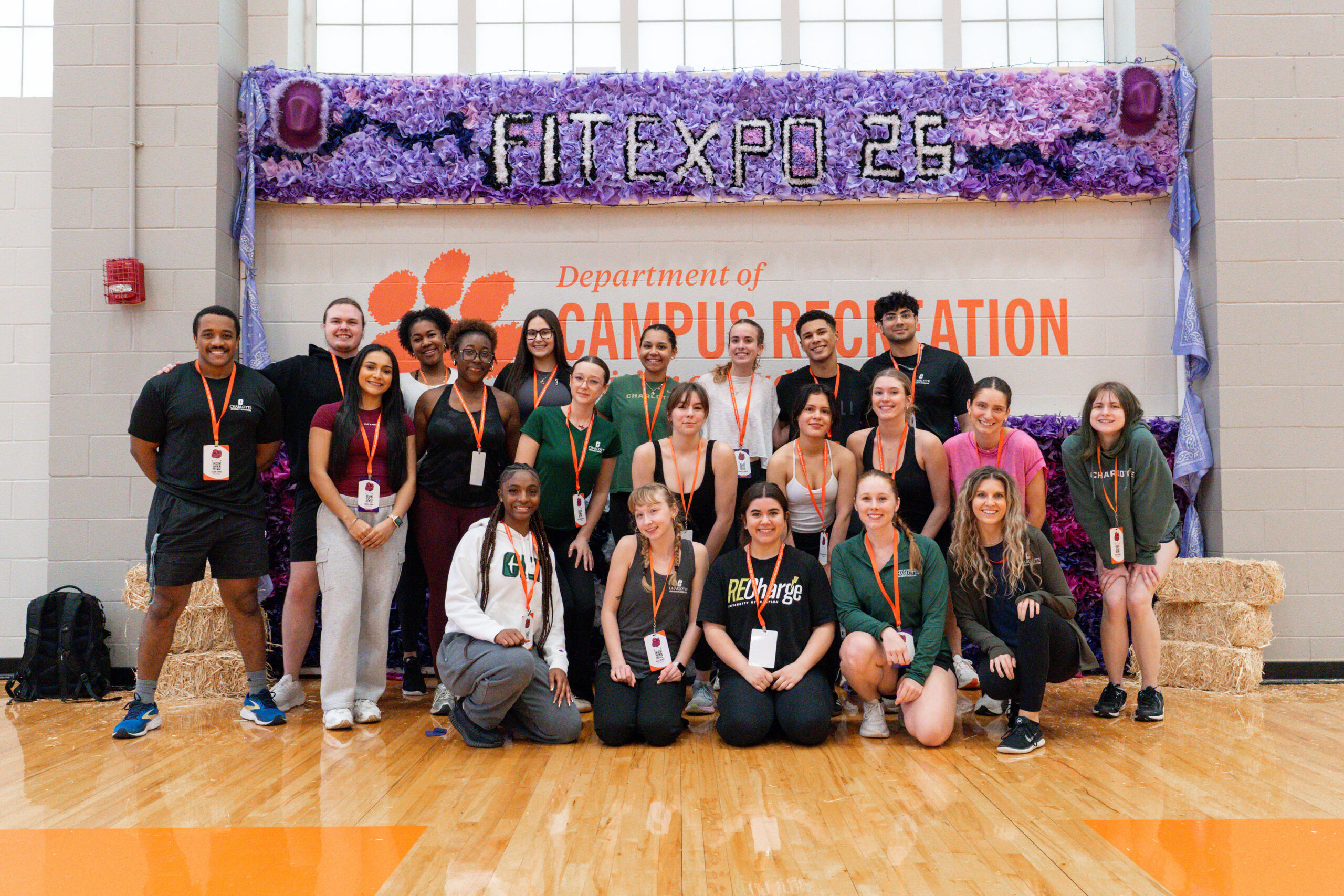 Collegiate fitness students posing in front of the FitExpo 26 banner at Clemson University campus recreation