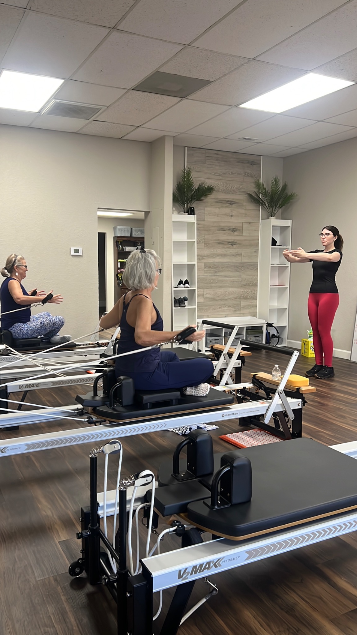 An instructor cues two active aging clients during a small-group Reformer Pilates class at The Training Toole studio in Ocala, Florida.
