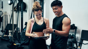 Fitness coach reviewing wearable health data with a client — precision wellness coaching framework 2026