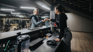 Gym operator reviewing a coach's schedule and rebooking numbers at a front desk