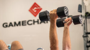 Coach personally correcting a member's strength-training form in a small-group session at a capacity-capped boutique studio