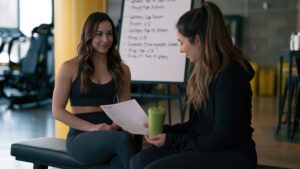 Fitness coach reviewing a client intake form and asking assessment questions before programming.