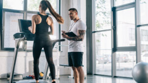 Fitness coach reviewing heart rate data with a client during a treadmill session.