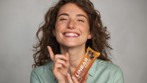 Female athlete and founder holding a clean whey protein bar she developed after an autoimmune health crisis