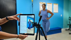 Fitness coach and gym member reviewing 3D movement assessment results together on a tablet.