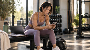 Coach at a gym front desk looking at a phone crowded with message notifications from several apps